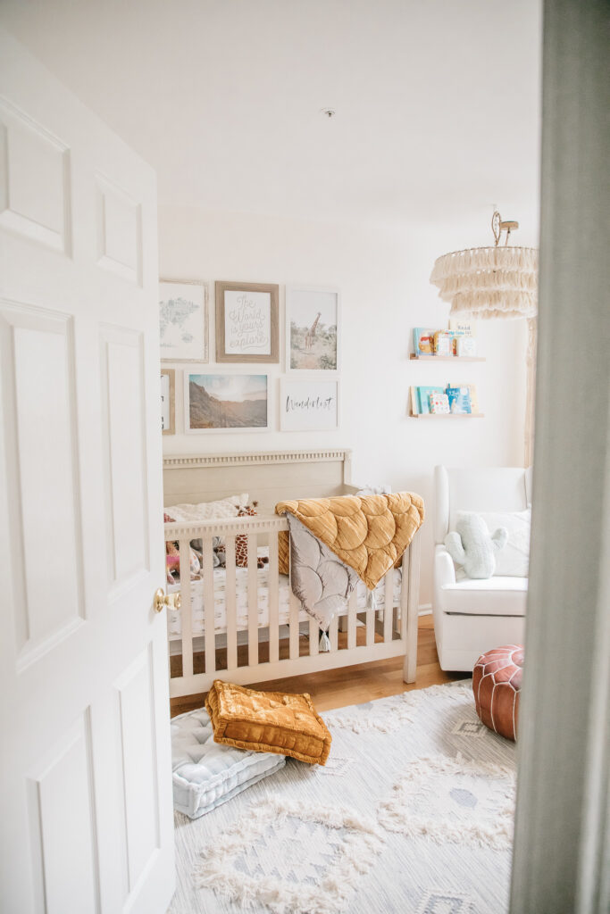 Decorative Floor Poufs. Boho nursery decor. Wanderlust theme nursery. Tassel chandelier, velvet floor cushions, Moroccan floor pouf, gallery wall and neutral crib and gliding chair. Boho shag rug.