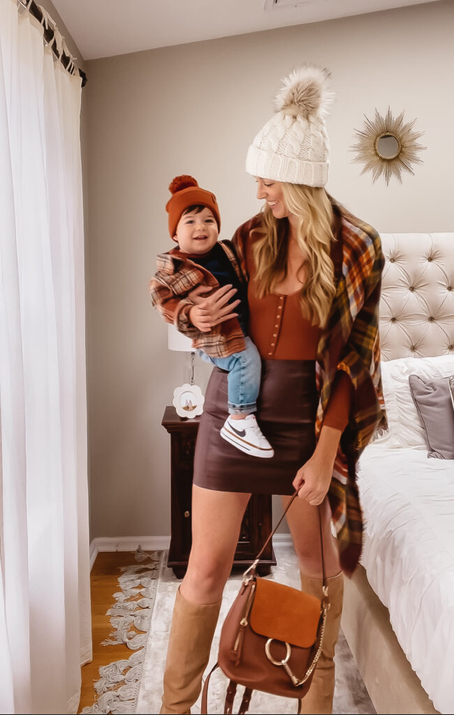 Fall Outfit Inspo: 7 Coordinating Mommy & Me Styles. Toddler boy fall outfit. Plaid shacket, baseball tee, toddler skinny jeans, toddler Nike sneakers, baby & toddler knit pom beanie hat. Women's knit pom beanie hat, fitted microthermal henley, faux leather mini skirt, fall plaid blanket scarf, knee high suede boots, and mini backpack.