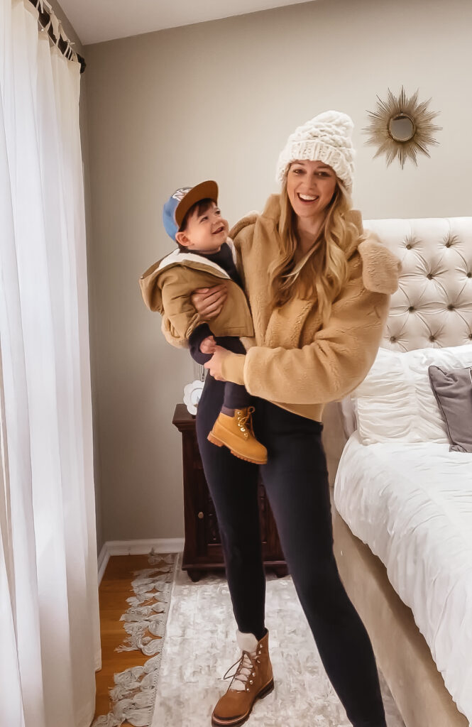 Fall Outfit Inspo: 7 Coordinating Mommy & Me Styles. Toddler boy fall outfit. Toddler thermal sweat set, toddler Timberland boots, NY flat brim hat & tan sherpa lined jacket. Women's black joggers, suede and sherpa combat boots, vintage wash crew neck pullover, sherpa bomber jacket & chunky knit pom beanie.