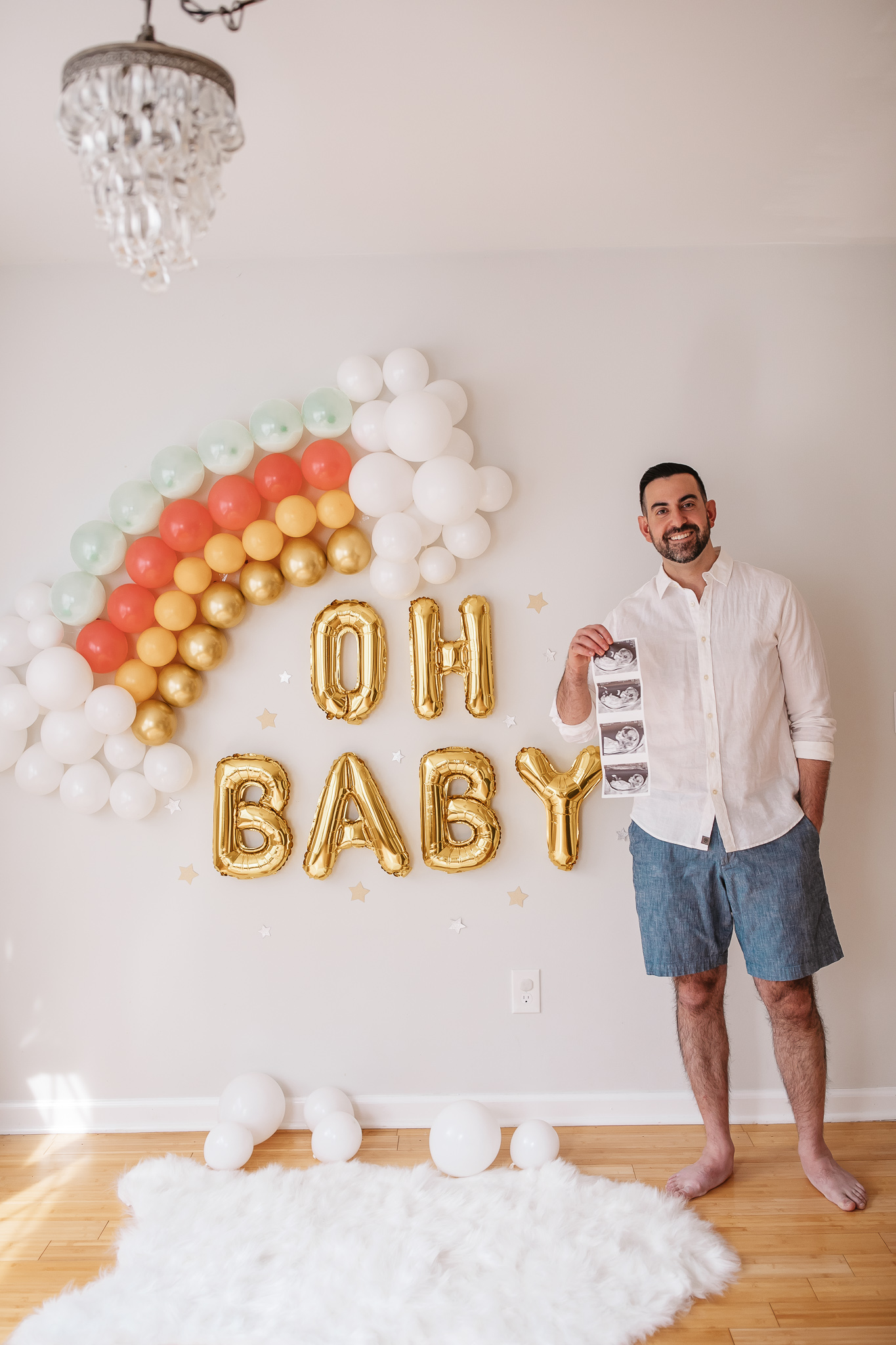 DIY Rainbow Baby Pregnancy Announcement. Daddy to be with the ultrasound. Rainbow baby balloon backdrop for photos.