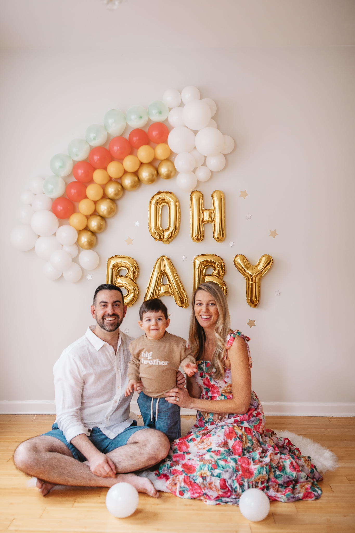 DIY Rainbow Baby Pregnancy Announcement. Family photos in front of rainbow baby balloon backdrop.