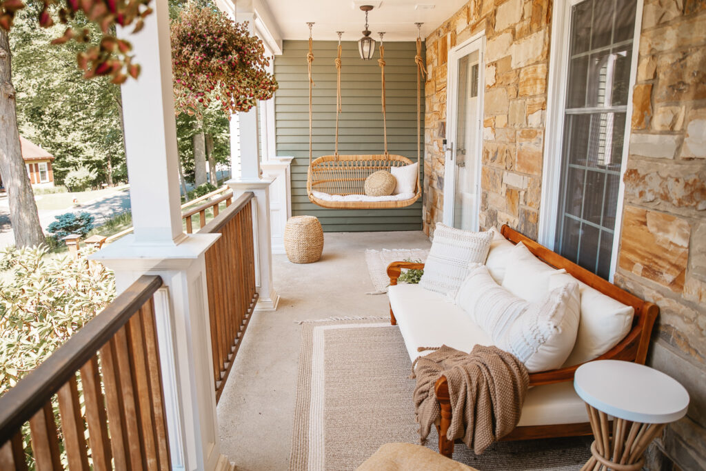 Neutral Front Porch Decor - Create a Front Porch Oasis. Hanging porch swing and oversized outdoor sofa. Hanging planters. Outdoor pillows. Natural materials and greenery.