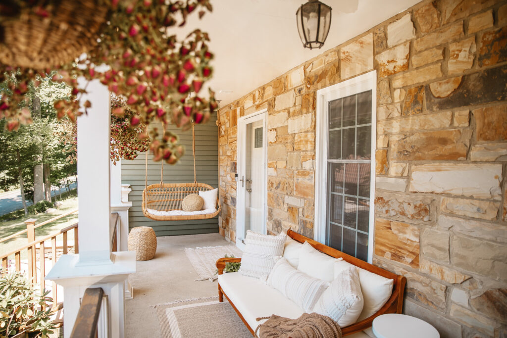 Neutral Front Porch Decor - Create a Front Porch Oasis. Hanging porch swing and oversized outdoor sofa. Hanging planters. Outdoor pillows. Natural materials and greenery.