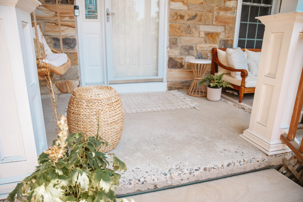 Neutral Front Porch Decor - Create a Front Porch Oasis. Hanging porch swing and oversized outdoor sofa. Hanging planters. Outdoor pillows. Natural materials and greenery.