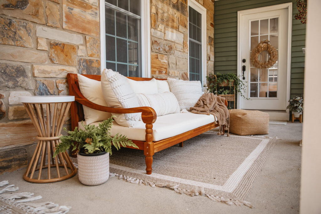 Neutral Front Porch Decor - Create a Front Porch Oasis. Hanging porch swing and oversized outdoor sofa. Hanging planters. Outdoor pillows. Natural materials and greenery.